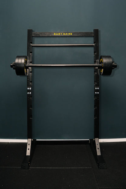 Kids Squat, Bench & Pull-Up Station, black frame with Baby Gains top bar, barbell with plates on the J-hooks, front view