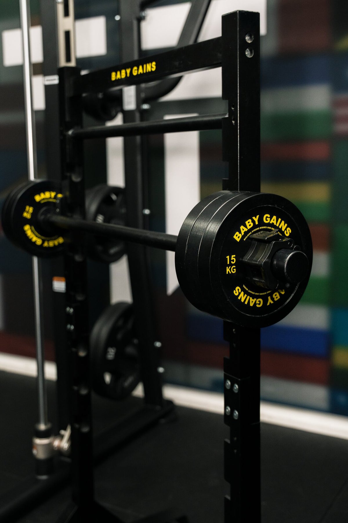 Kids Squat, Bench & Pull-Up Station with Baby Gains plates on the barbell in a gym